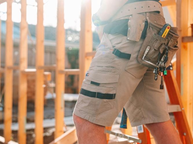 A person with a tool belt on at a construction site.