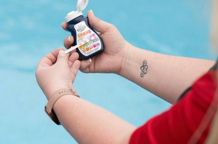 A pH testing kit being used to test pool water