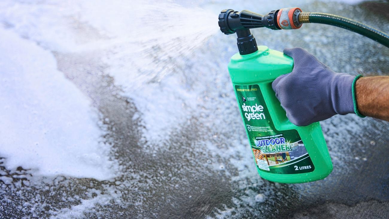 Green Simple Green outdoor cleaner bottle being held by a gloved hand