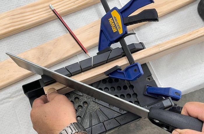 Drawer front, back and side pieces being cut with angled ends using a mitre box and handsaw.