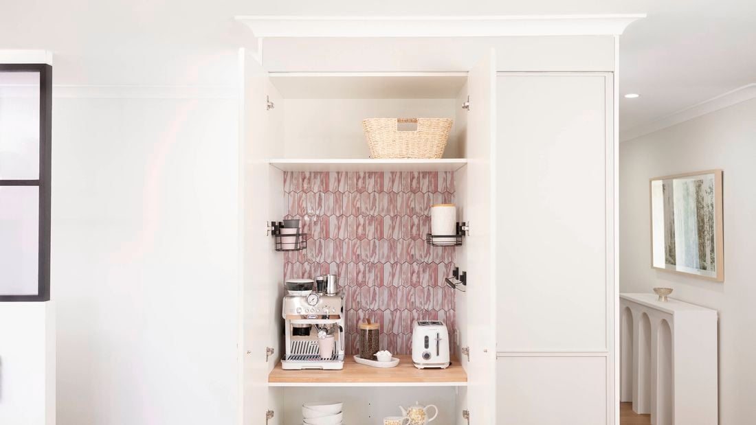 A picture of a white appliance cupboard with decorative adhesive tiles on one of the shelves in the room
