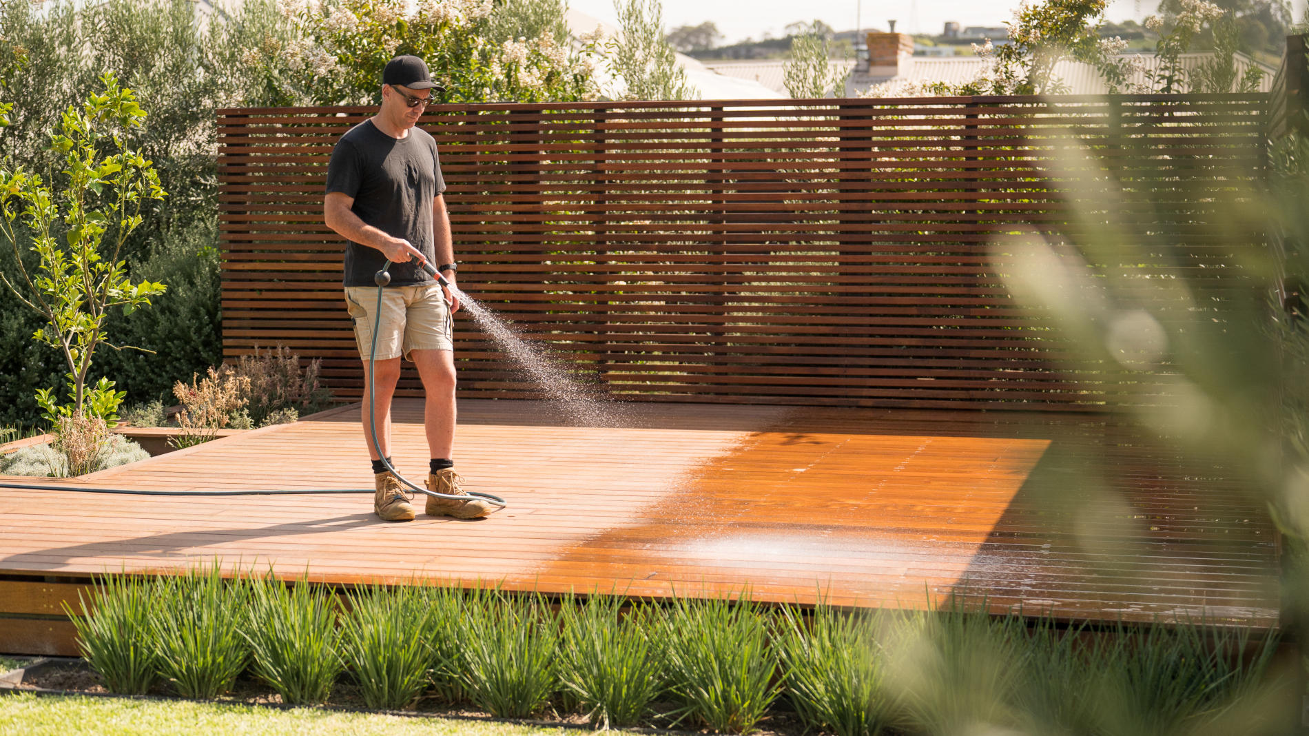 Man using hose to wet a deck