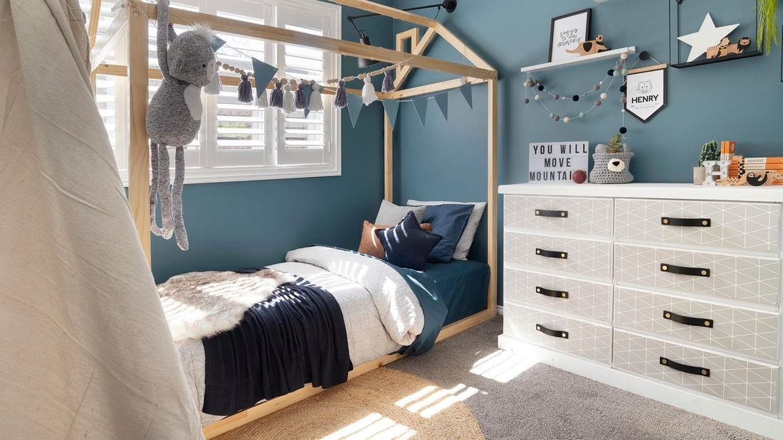 Kids bedroom with timber bed frame, bunting and toys.