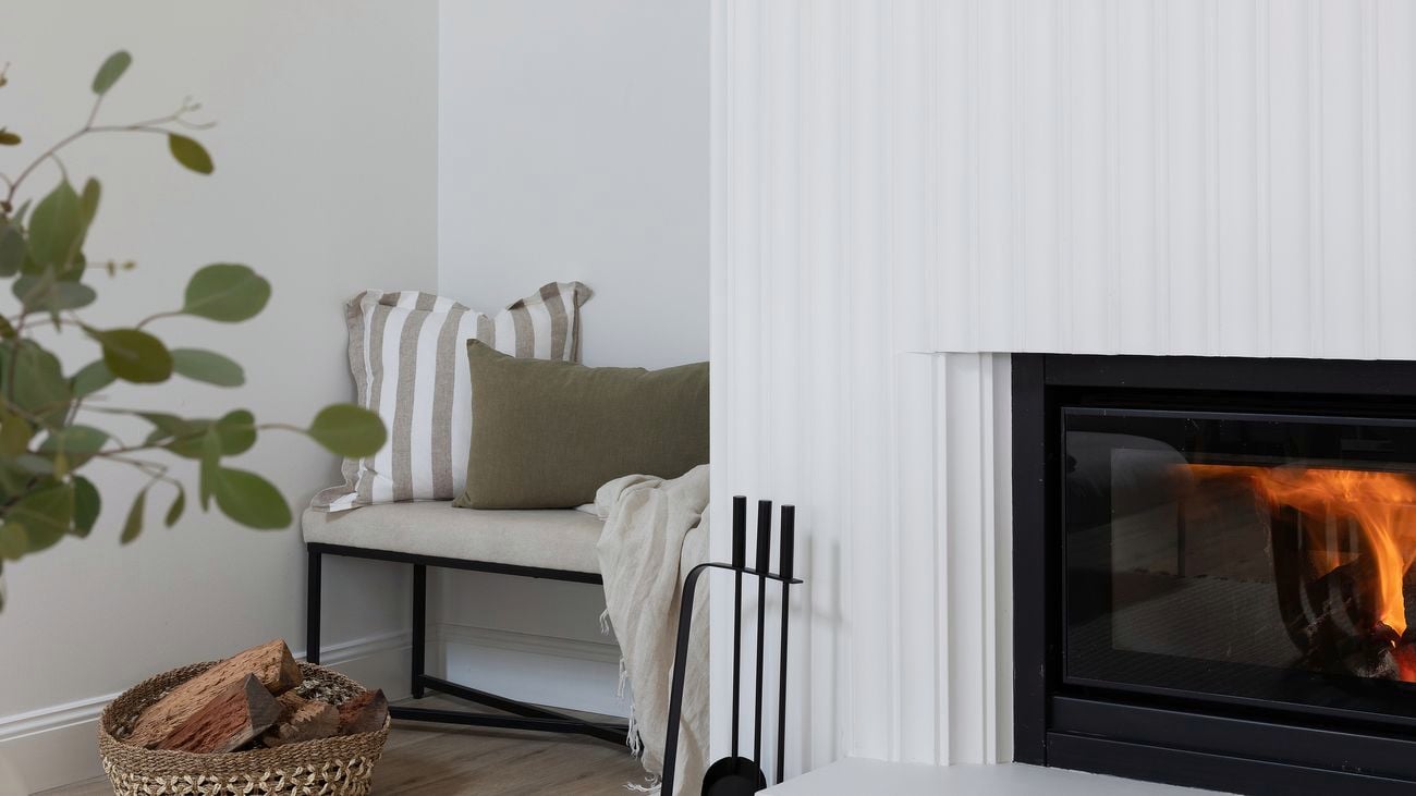 Fireplace and chair next to white staircase.