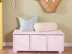 Pinked coloured hallway storage cabinet with several cushions neatly arranged on top of it.
