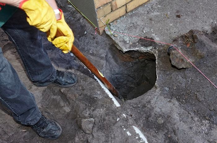 A hole cut into concrete and the earth below for a post to be set out