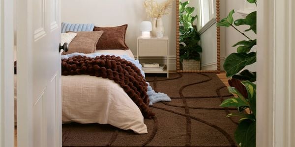 Bedroom interior with a neatly made bed, floor mirror, and indoor plants