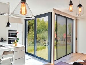 Open bright kitchen area with black framed flyscreen doors and hanging pendants