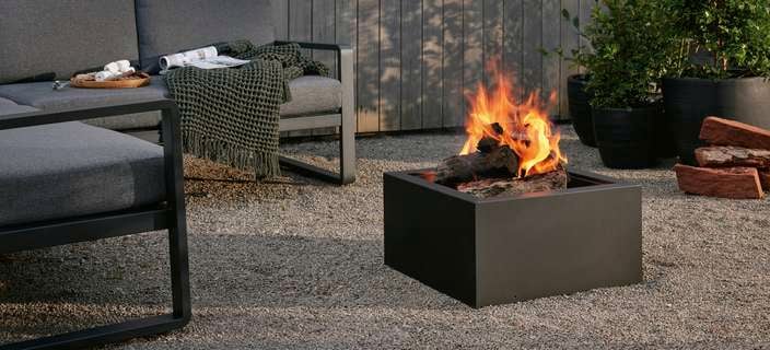 An outdoor setting and a fire pit outside on a pebbled area.