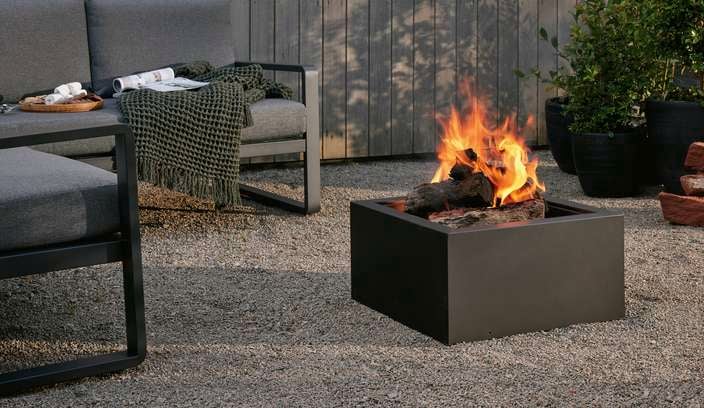An outdoor setting and a fire pit outside on a pebbled area.