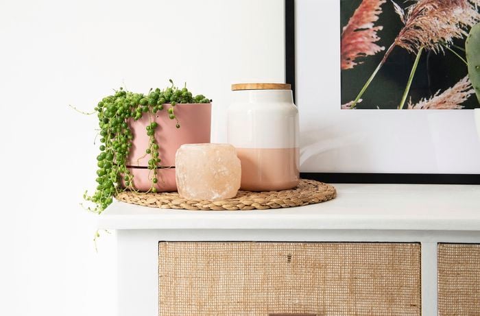 A string-of-pearls plant in a pot with another decorative pot on top of a white storage unit