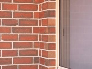 The image displays a brick wall with a half window.