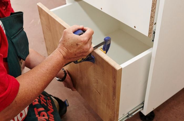 Person using clamps to install cabinet panels