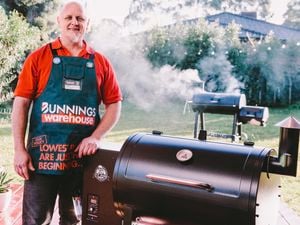 Man standing next to a pellet smoker