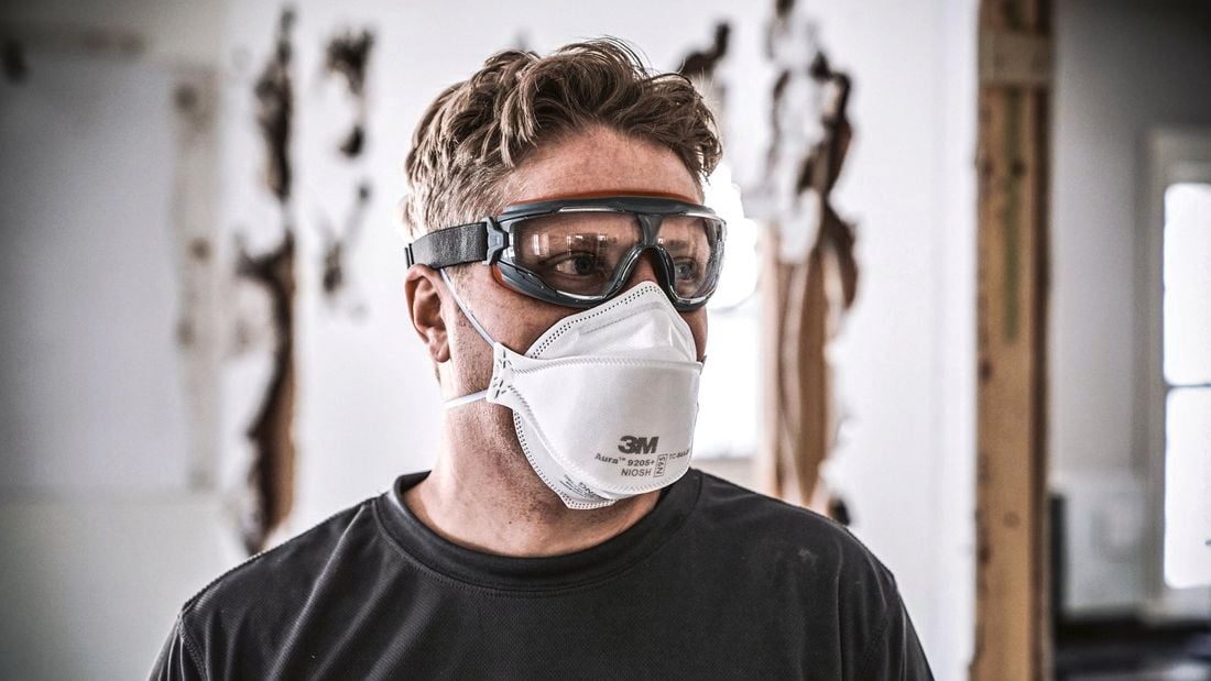 A tradesman wearing safety goggles and a protective mask