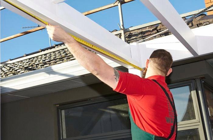 A person measuring the beam of a pergola
