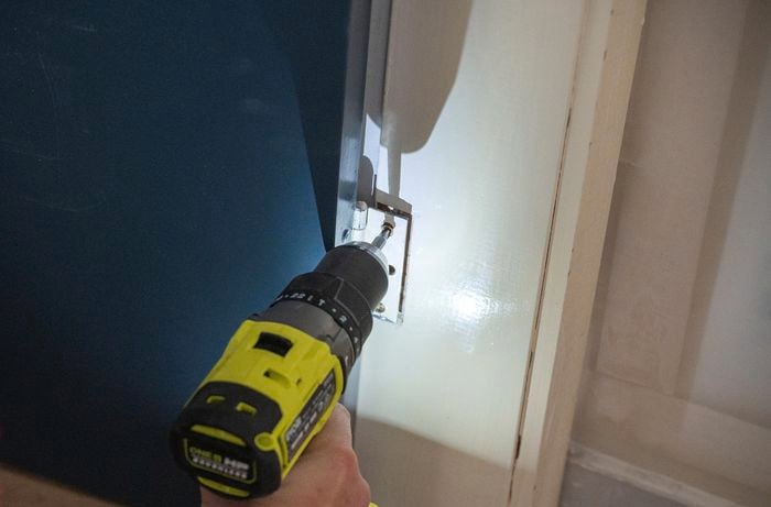 A person installing the door using an impact driver.