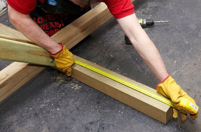Person measuring piece of timber with measuring tape.