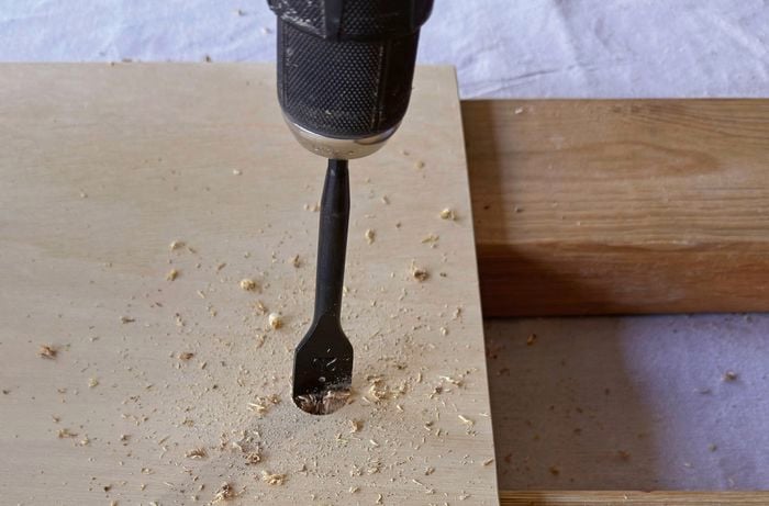 A spade bit making a hole in a piece of wood