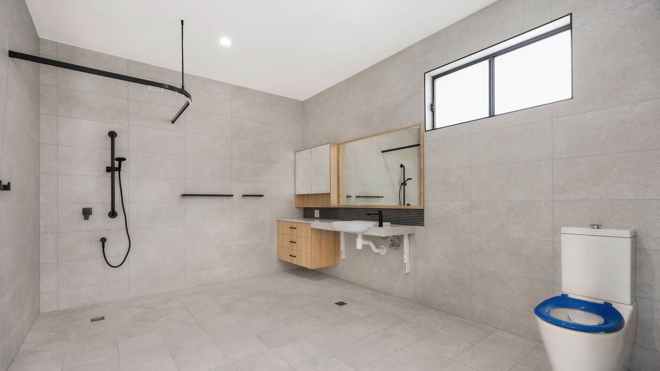 The inside of a large bathroom fitted with products from Bunnings Trade’s Specialist Disability Accommodation range