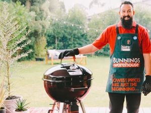 Man standing next to a kettle smoker