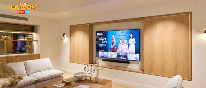 Contemporary living room featuring neutral sofas, a timber coffee table and wall-mounted TV framed by built-in timber cabinetry.