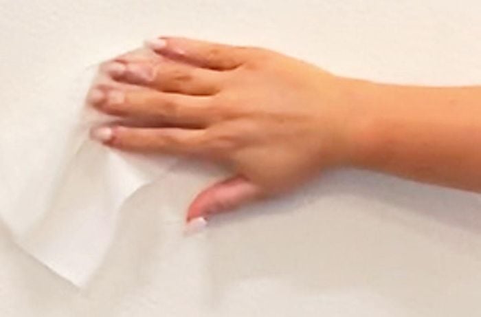 Hand cleaning wall with sugar soap wipe.