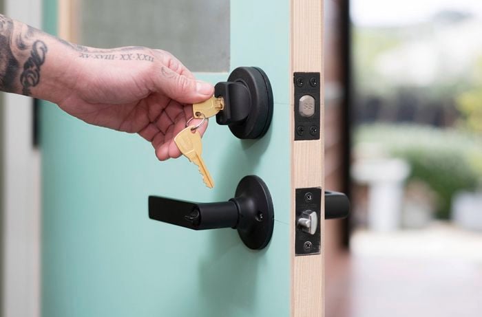 A person is testing a newly installed deadbolt by locking and unlocking it multiple times to ensure smooth functionality