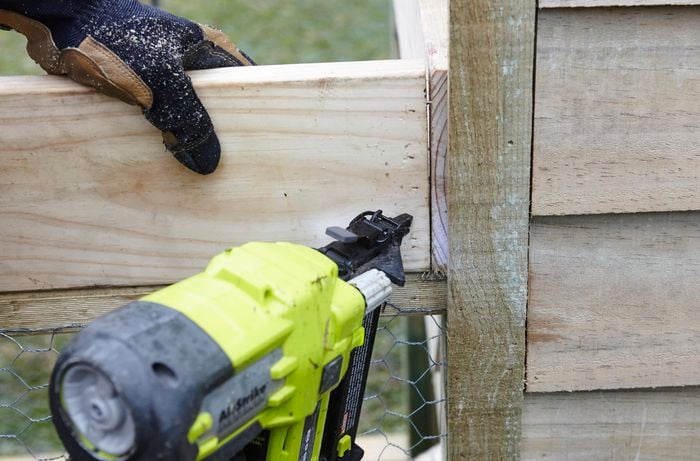 The side panels of a planter box being nailed into place on the roof of a chicken coop