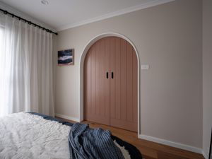 Arch frame with a clay coloured barn door in a bedroom.