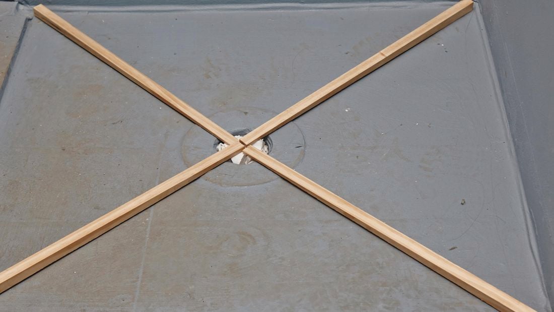 Four wedge-shaped lengths of timber laid in an X across a shower base