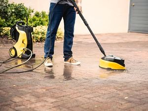 A person cleans outdoor pavers with a Kärcher water blaster