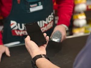 Bunnings customer presenting something on their smartphone to a Bunnings Team Member who is behind the counter.