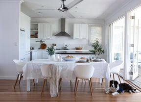 Modern kitchen and dining area with white decor, ceiling fan and dog