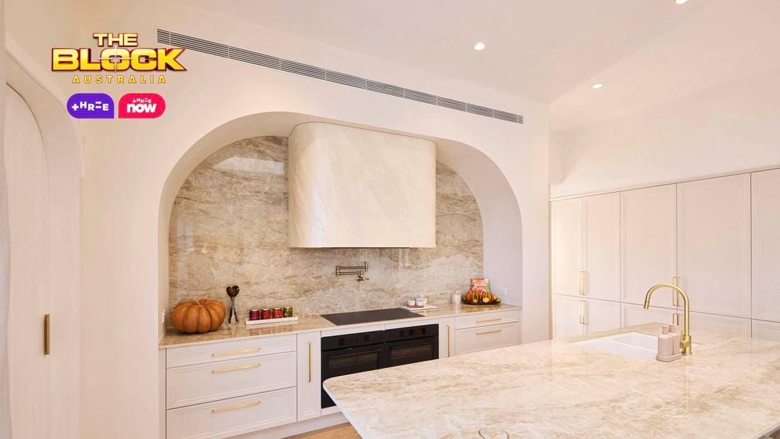 Modern kitchen from The Block with marble island, arched cooking nook, white cabinetry, and stone backsplash.