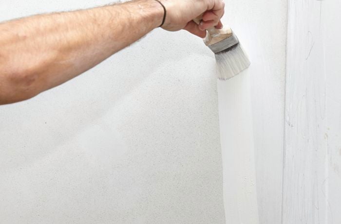 White paint being applied to a wall with a paint brush