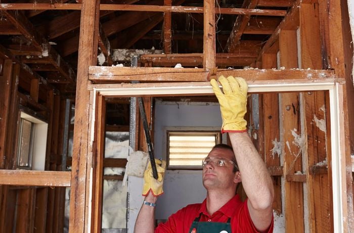 A Bunnings team member using a wrecking bar to pry a door jamb out of a wall frame