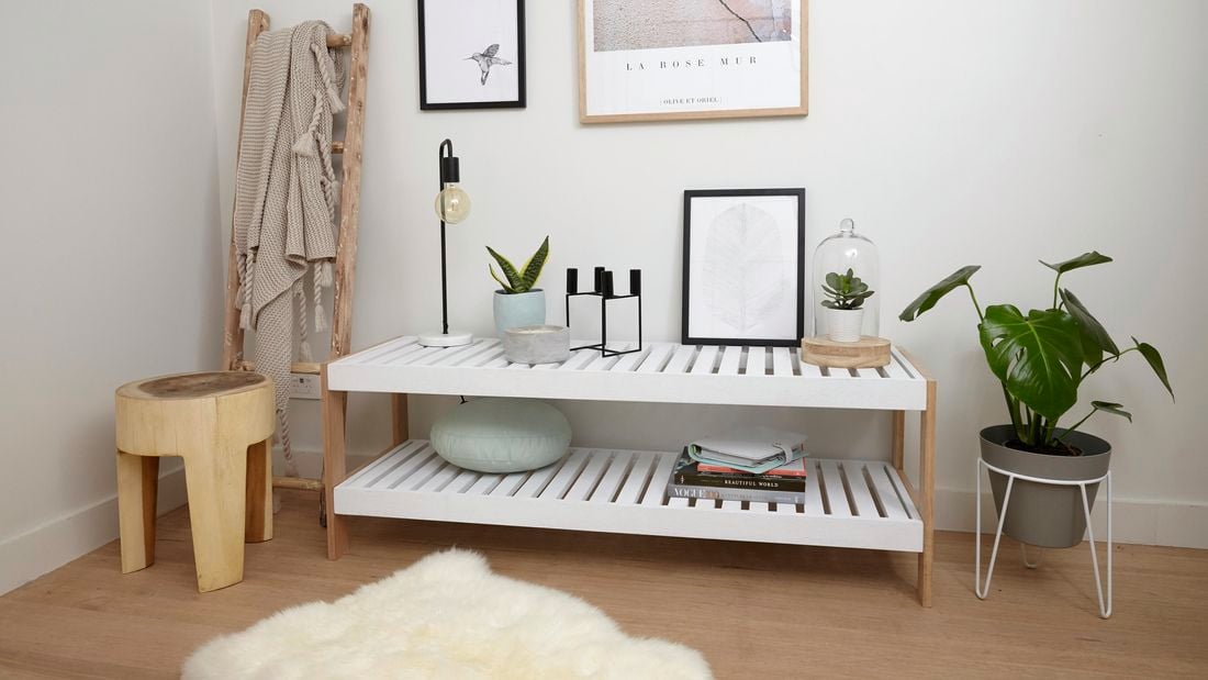 A slatted shelving unit in a brightly lit wooden themed room with a fur rug on the floor
