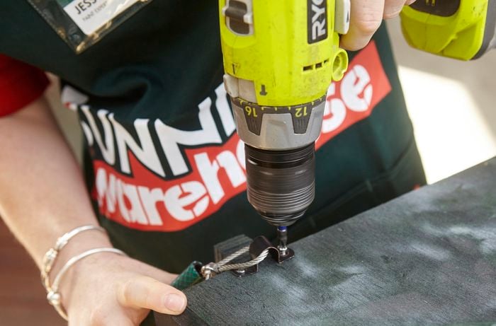 A loop being drilled into a completed bird box with wire to secure it to a tree