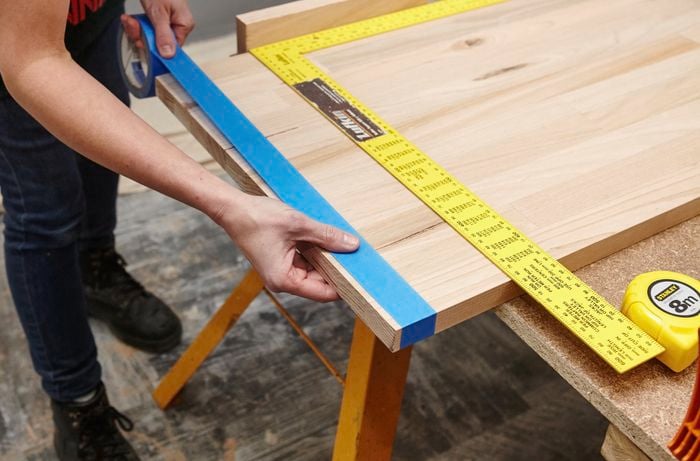 Person putting masking tape on a timber panel