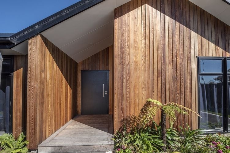 Exterior of a timber-clad house with a recessed entry and dark grey front door