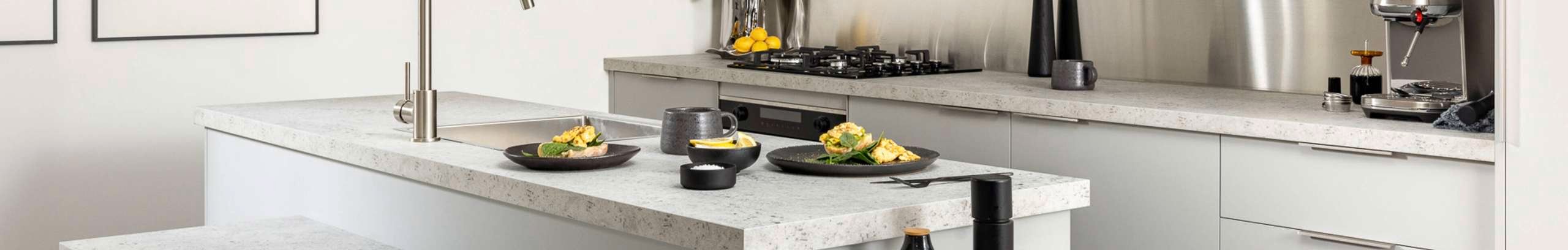 Light grey modern kitchen with a marble benchtop, black crockery and a coffee machine on the bench.