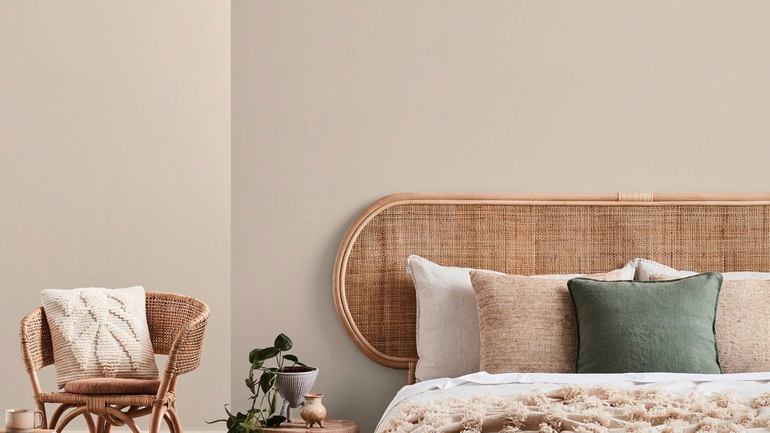 Bedroom with beige walls, a bed, a side table and a chair in it.