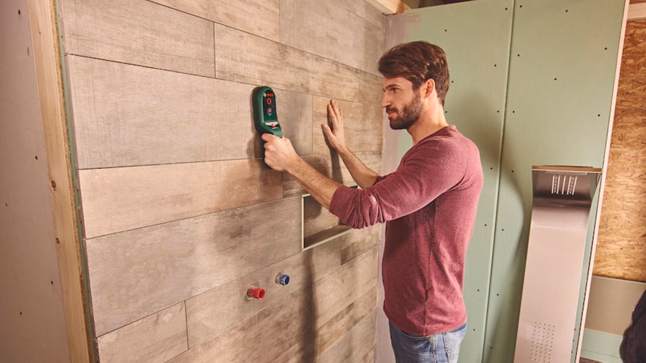 Man using a Bosch wall scanner on a timber wall.