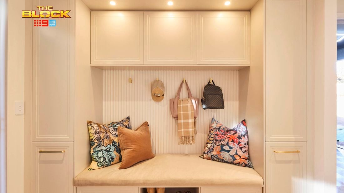Mudroom nook from The Block with built-in bench, overhead cupboards, cushions, hooks, and shoe storage.