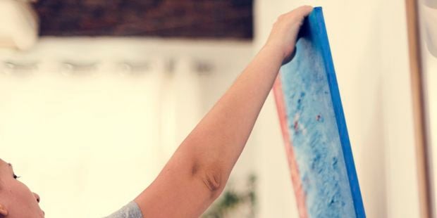 woman hanging portrait on a wall