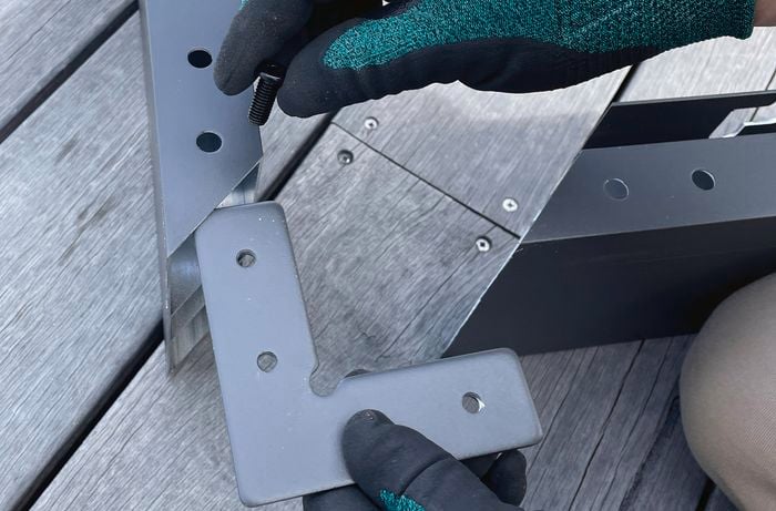 Person securing L connectors to the frame of a gazebo with hex bolts.