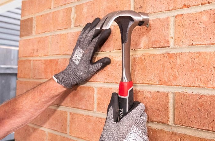 Person hammering wall plugs into brick.