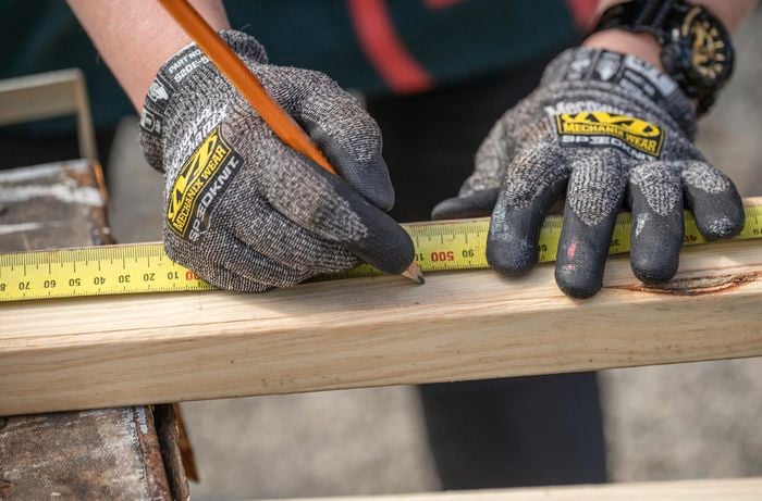 Person marking the timber with tape measure and pencil.