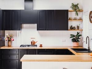 Kitchen with black cabinetry and timber benchtops.
